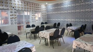 A conference room with multiple tables and chairs, patterned walls, and a ceiling with a colorful design.