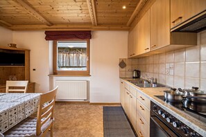 A kitchen with wooden cabinets, a window with curtains, a radiator, and a stove.