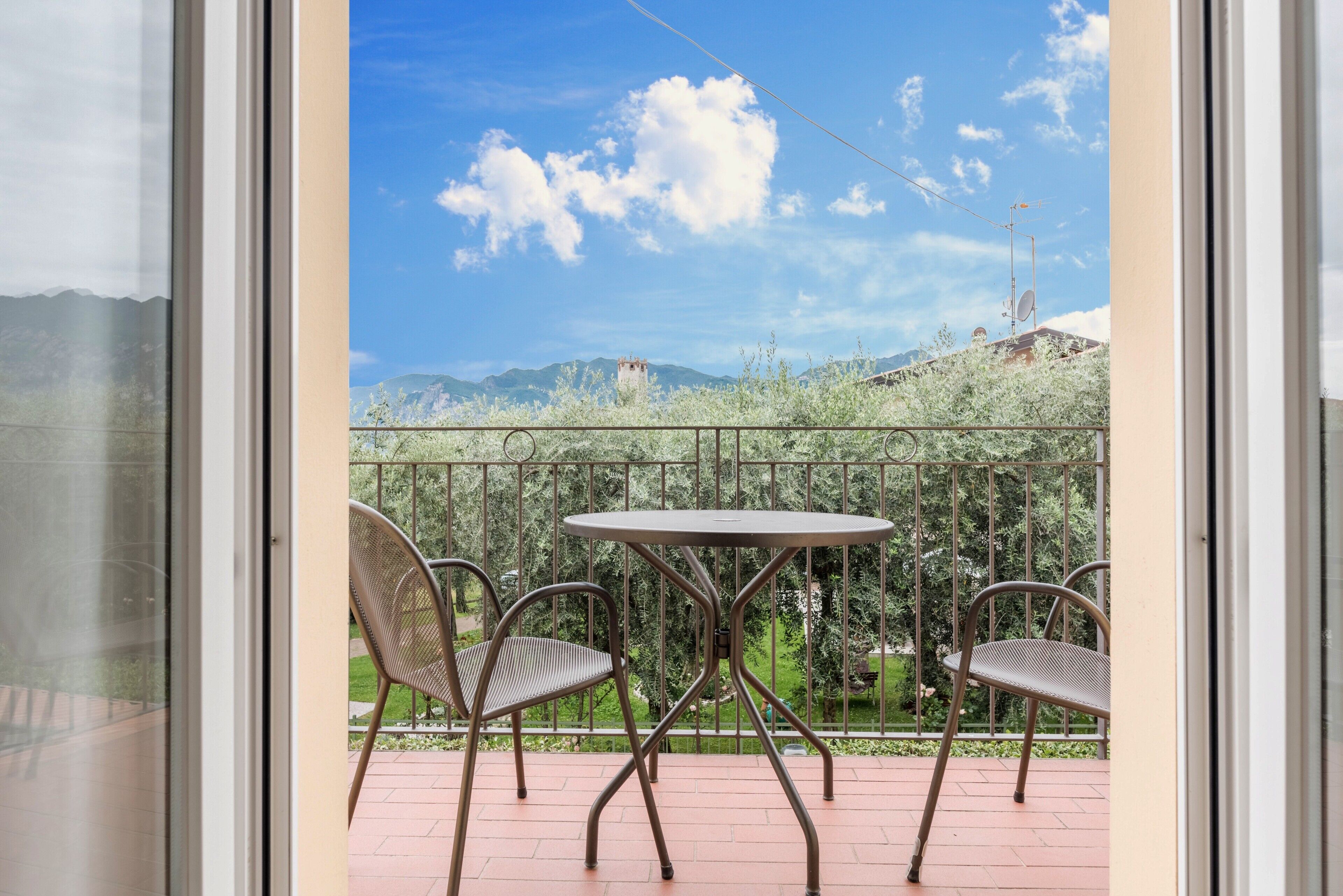 Ein Balkon mit Tisch und Stühlen, Blick auf Berge und einem klaren Himmel.