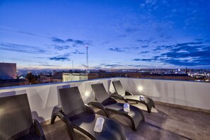 A rooftop terrace with four lounge chairs, a clear view of the cityscape, and a communication tower in the distance. - Tritoni Hotel Deluxe room (Floriana)