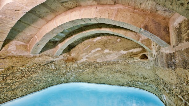 Un techo de piedra arqueado con una piscina en la parte inferior.