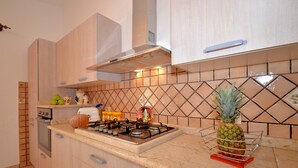 Una cocina con estufa a gas, armarios de madera, microondas y salpicadero de azulejos.