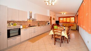 Una cocina con armarios de madera, una estufa y un comedor con mesa y sillas.