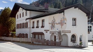 A traditional building with a mural, a wooden fence, and a cobblestone street.