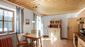 A wooden ceiling, a dining table with chairs, a kitchen area with cabinets, and a radiator.