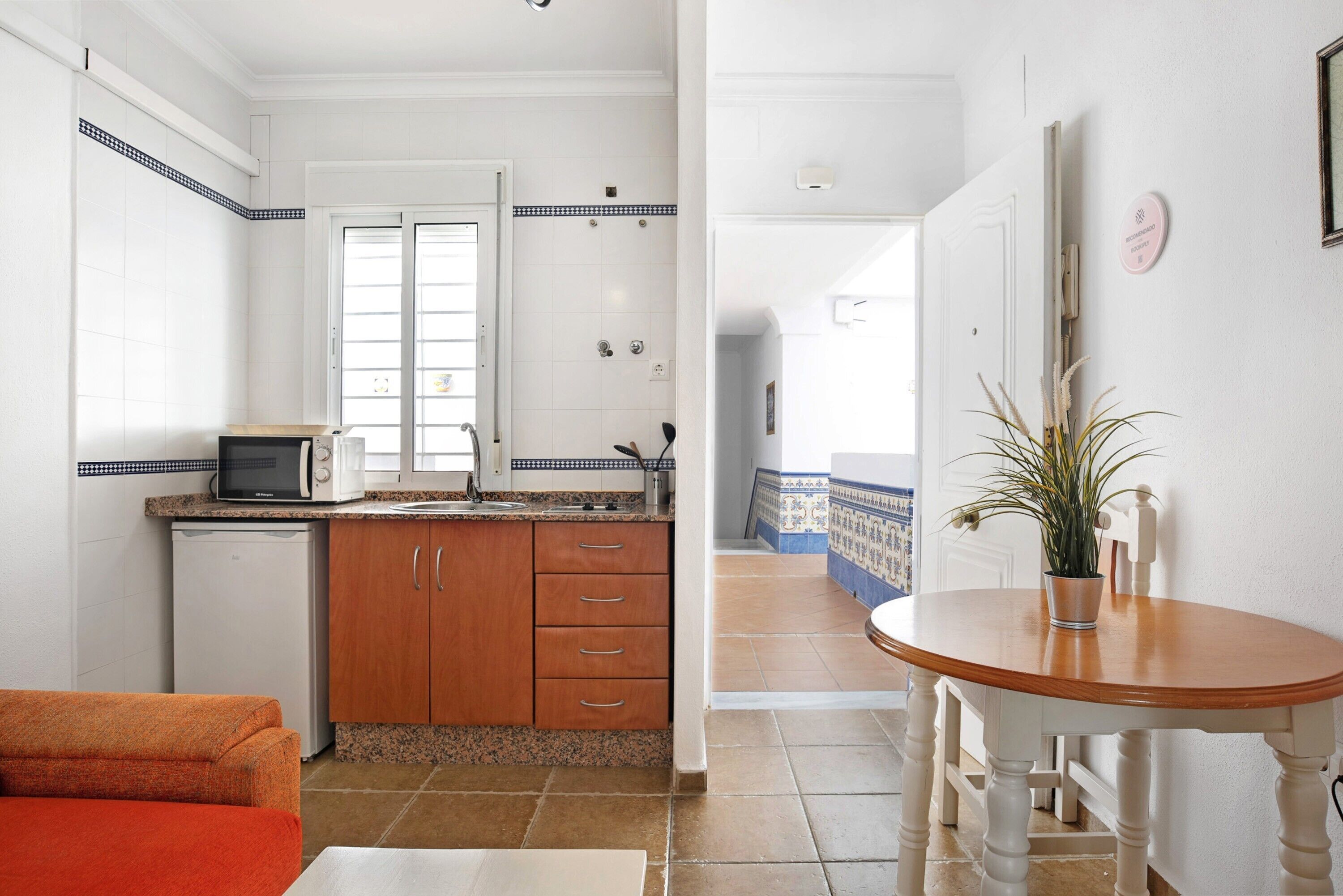 A compact kitchen with a microwave, refrigerator, and wooden cabinets.