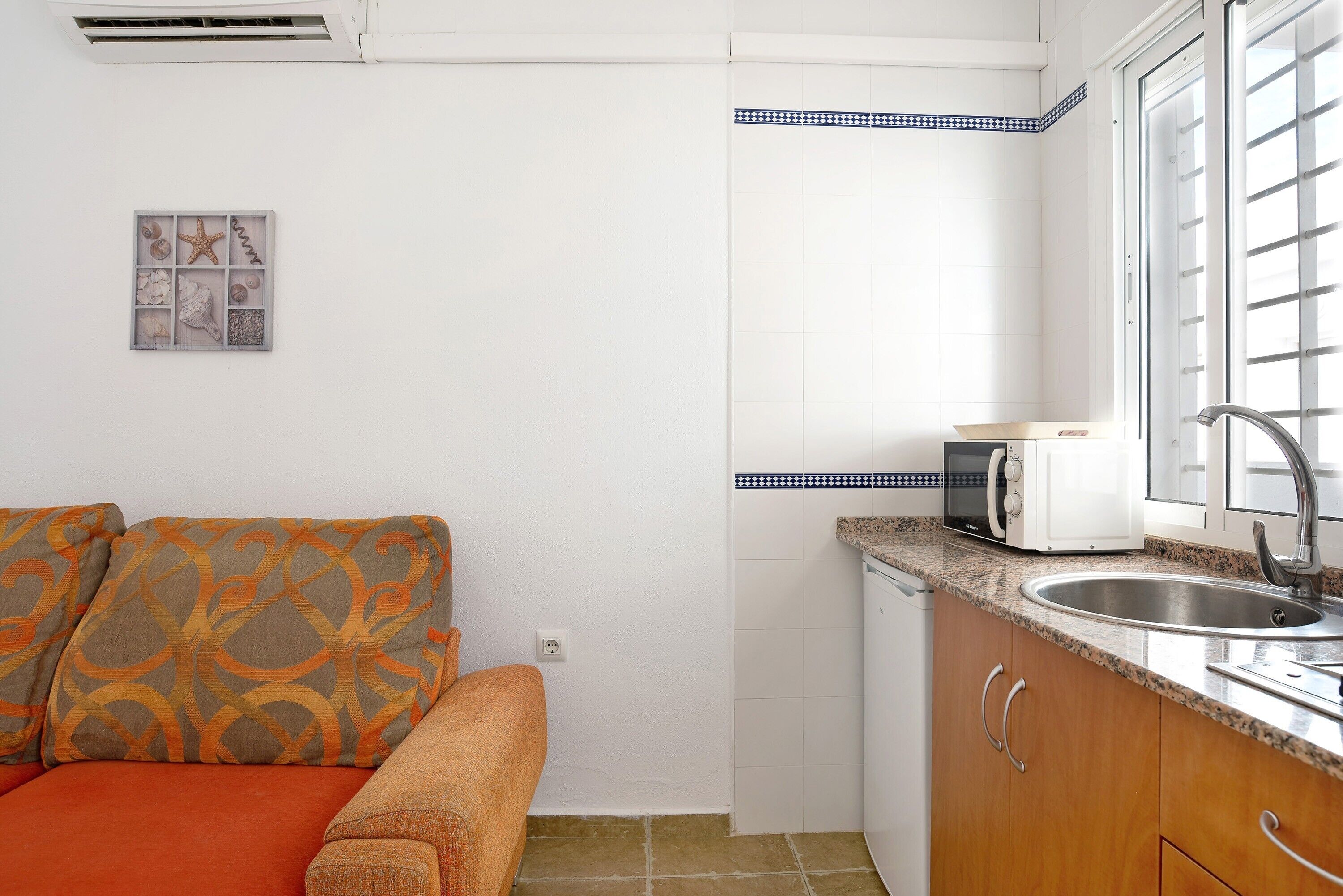 A compact kitchen with a microwave, sink, and a small window.