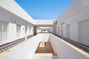 A long corridor with white walls, tiled flooring, and a central open space.