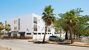 A white building with a 'CAMPO & HOGAR' sign, palm trees, and a parked car.