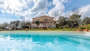 A pool with clear blue water, a stone building with a covered patio, and surrounding greenery. - Majorcan Finca with Pool - Son Draguet (Porreres)