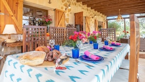 A long dining table set with food and drinks, wooden furniture, and a stone wall backdrop. - Majorcan Finca with Pool - Son Draguet (Porreres)