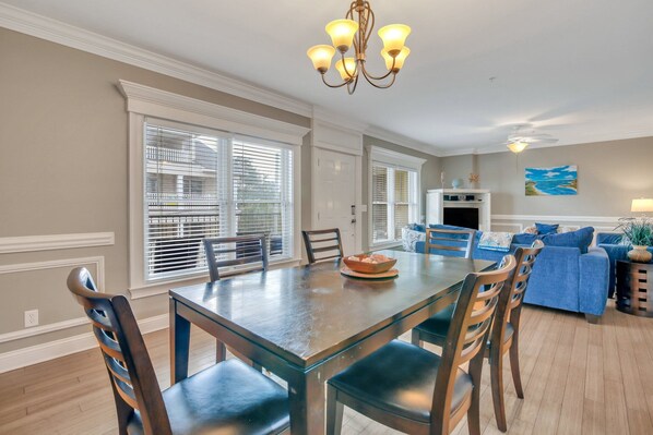 A dining area with a glass-top table, wooden chairs, and a chandelier.
