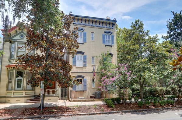 A two-story building with a beige facade, multiple windows, and a porch. - Heated Pool Access | 5*Clean | Flex Cancelation (Savannah)