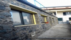 Een gebouw van steen met grote ramen en een betonnen pad.