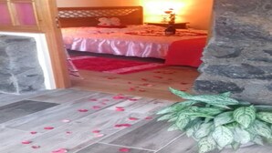 Een slaapkamer met een bed, nachtkastje, lamp en een potplant.