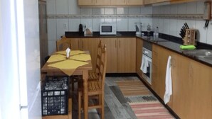 Een keuken met houten kastjes, een magnetron en een eettafel met stoelen.