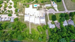 An aerial view of a property with multiple buildings, a swimming pool, and surrounding greenery. - RG 111 Guadalupe Fortress of Awesome (New Braunfels)