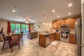 A modern kitchen with wooden cabinets, stainless steel appliances, and a dining area with a table and chairs.