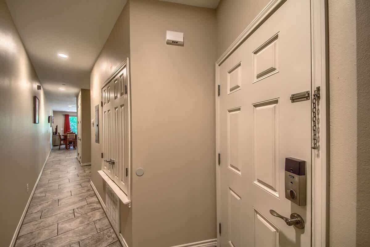 A hallway with a wooden floor, white doors, and a small sign on the wall.