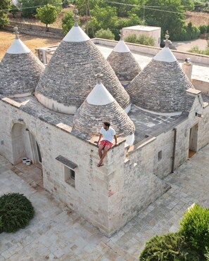 A stone building with multiple conical roofs and a person standing on the roof.