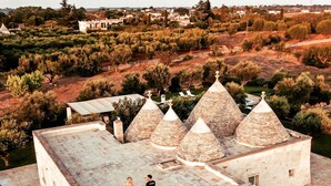 A stone building with a flat roof and multiple conical structures on top. - Luxury Villa "Trulli Terrarossa" in Apulian style with Pool (Martina Franca)
