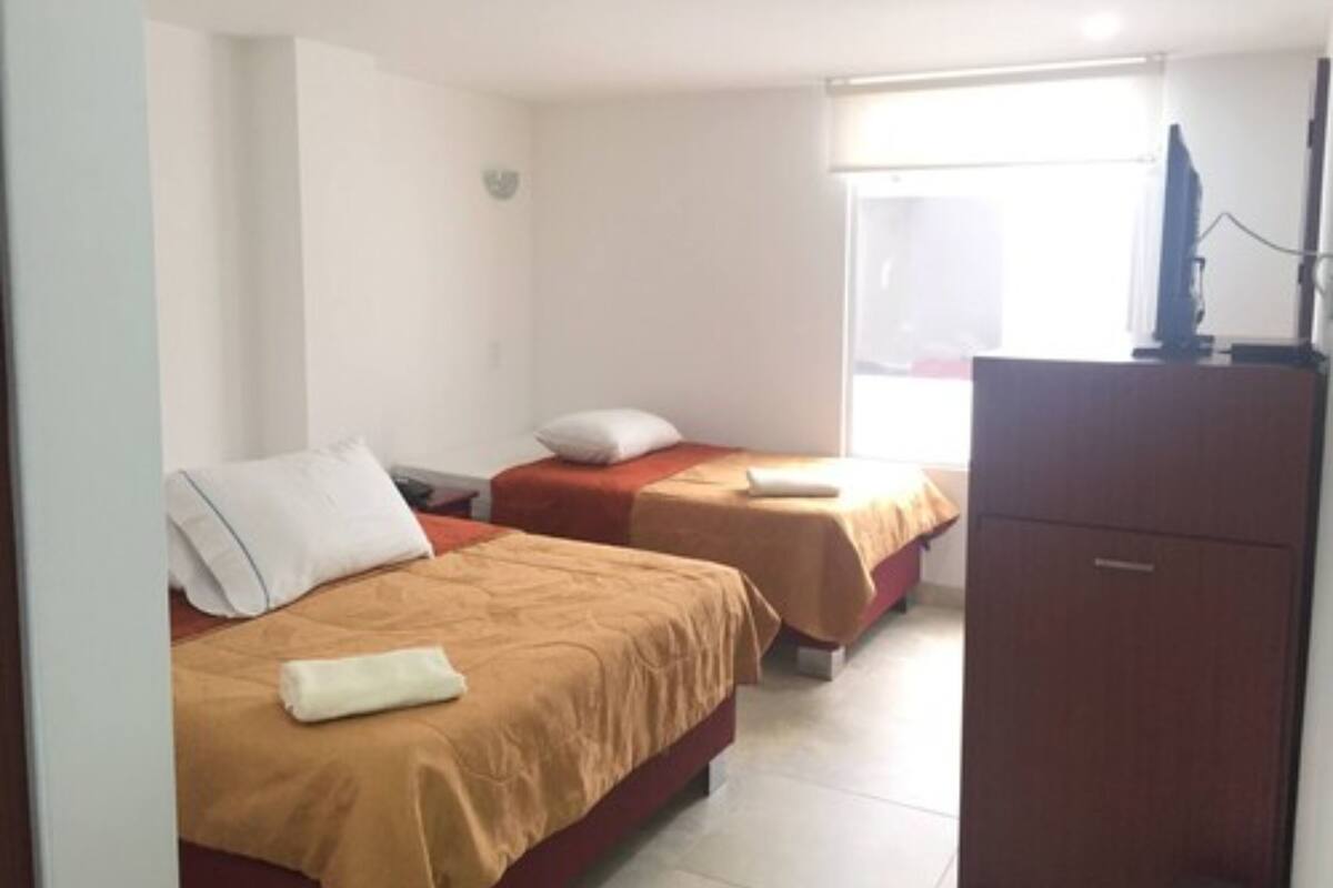 A hotel room with two beds, a TV, and a desk.
