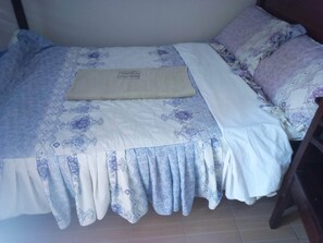 A bed with a floral-patterned bedspread and pillows, a beige blanket, and a headboard. - Aroma Guest House (Wote)