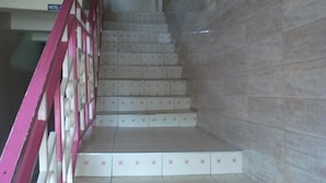 Un escalier avec une rampe rose, menant à un étage supérieur.