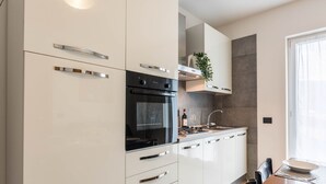 A modern kitchen with white cabinets, a black oven, and a dining area with a table and chairs.