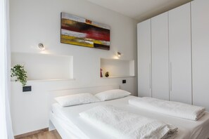 Une chambre à coucher comprenant un lit, des tables de chevet, une œuvre d’art accrochée au mur et une armoire.