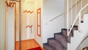 Una escalera con barandilla, piso de madera y alfombra roja.