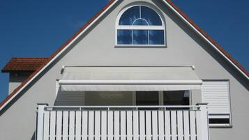 A residential building with a gabled roof, a balcony with white railings, and a garage door.