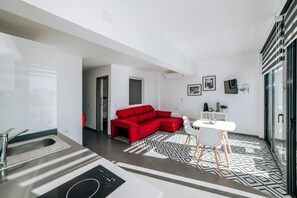 Un intérieur moderne comprenant une cuisine, un canapé rouge, un coin repas et un sol à motifs.