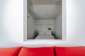 Une petite pièce comprenant un lit, une petite table et une plante en pot.