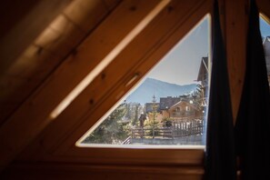 Une lucarne triangulaire offrant une vue sur les bâtiments et les montagnes.