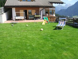 Une maison avec un patio, un toboggan et une vue sur les montagnes.