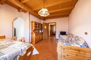 Une pièce avec un plafond en bois, une table à manger avec des chaises, un canapé, un meuble et un téléviseur.
