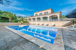 A pool area with a stone pool, lounge chairs, and a building with a balcony. - Rural Idyll Villa "Sa Pleta" with Pool (Petra)