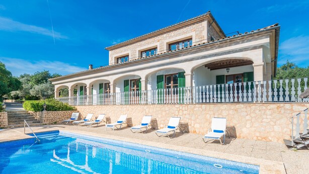 A poolside area with lounge chairs and a stone building with arches. - Rural Idyll Villa "Sa Pleta" with Pool (Petra)