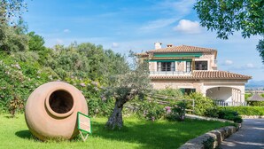 A two-story house with a tiled roof, a large clay pot, and a sign in a grassy area. - Rural Idyll Villa "Sa Pleta" with Pool (Petra)