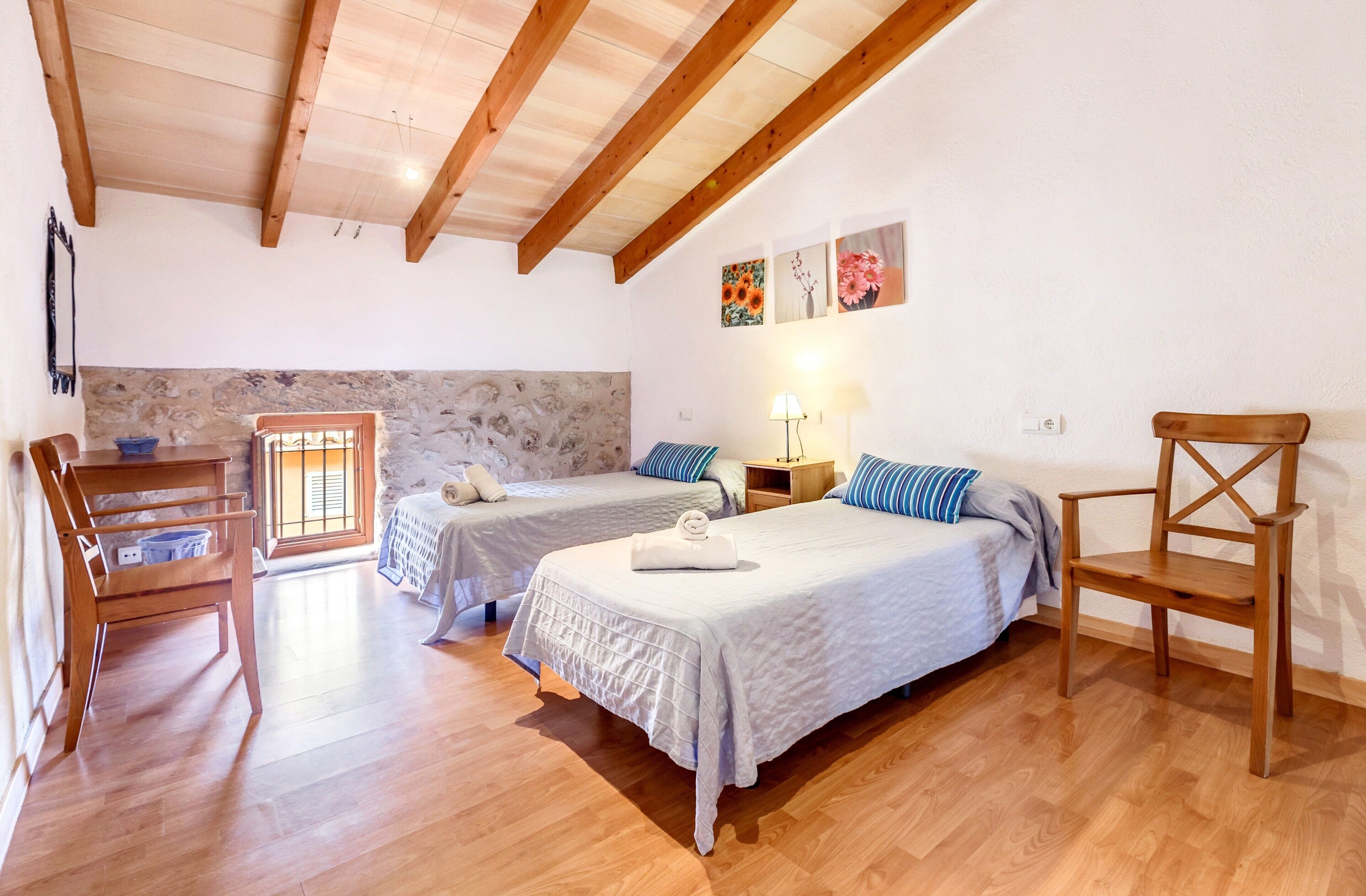 Une chambre avec deux lits, un plancher en bois, un mur en pierre et un plafond en bois.