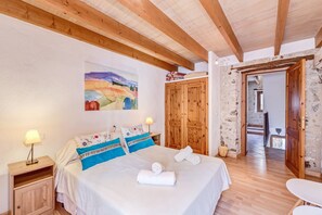 A bedroom with a bed, wooden wardrobe, and a painting on the wall.