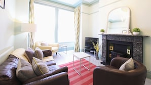 A living room with a fireplace, a sofa set, a television, and a large window.