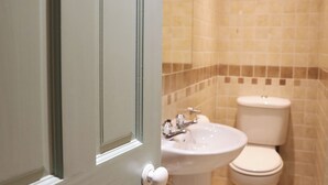 A bathroom with a white sink, a toilet, and a shower area.