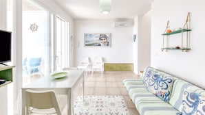 A modern living room with a sofa, a dining table with chairs, a TV, and a painting on the wall.