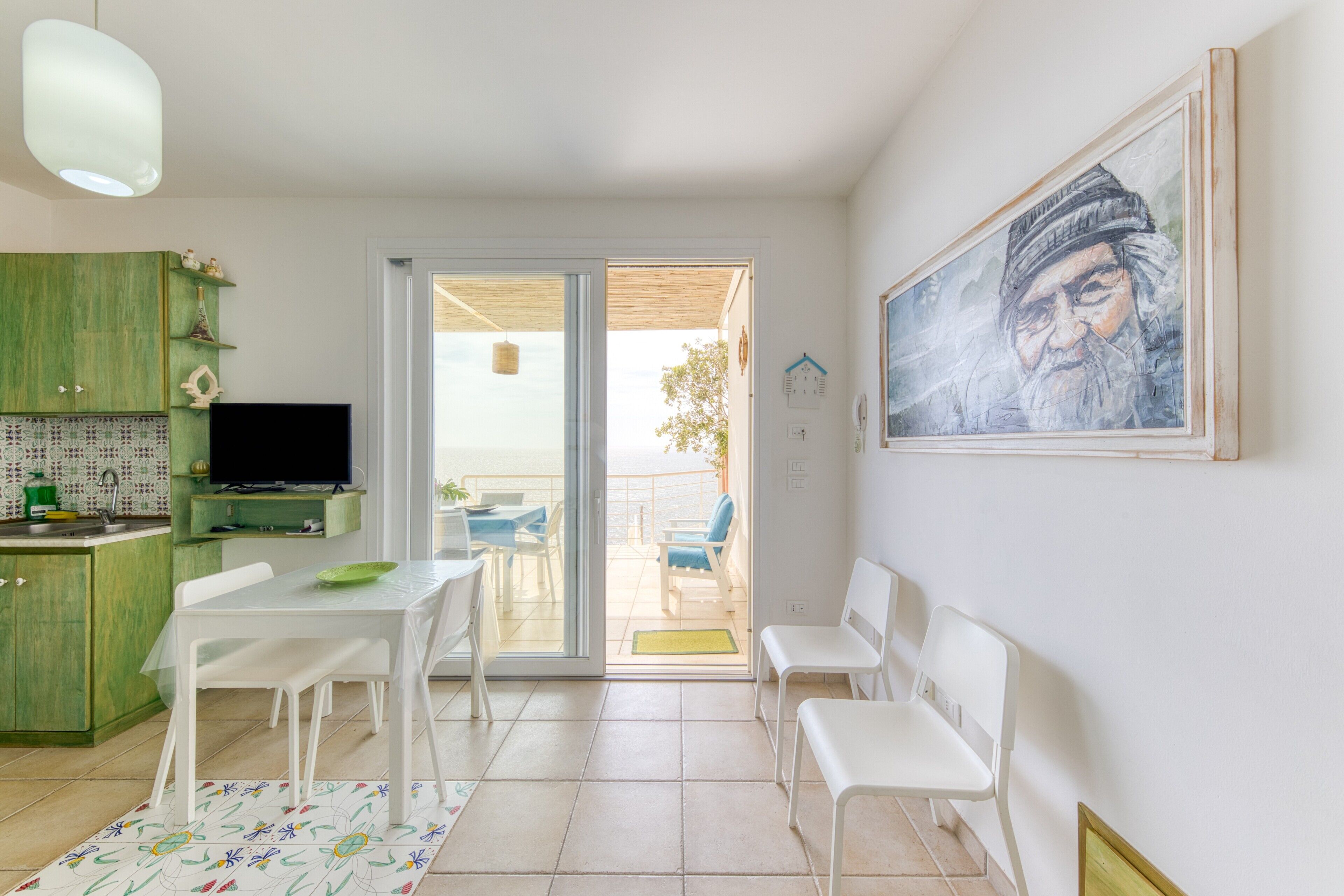 Eine moderne Küche mit Fernseher, Esstisch, Stühlen und einem grünen Schrank.