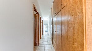 A hallway with wooden cabinets, tiled flooring, and a view of a car outside.