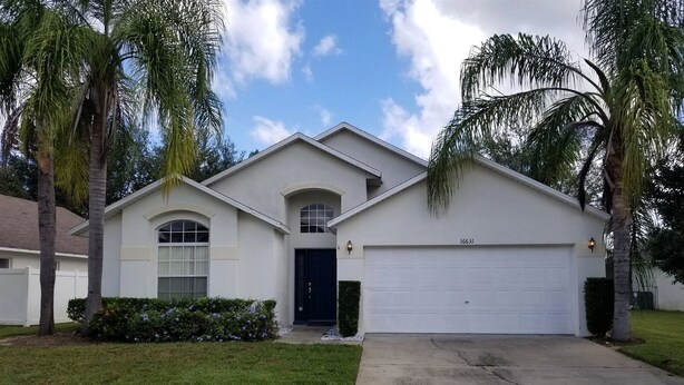 A single-story house with a garage, a front door, and a small front yard with grass and bushes. - Rising Star in Clermont (Clermont)
