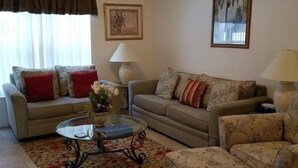 A living room with two sofas, a coffee table, a ceiling fan, and a painting on the wall. - Rising Star in Clermont (Clermont)
