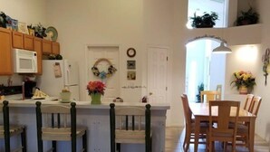 A kitchen with a central island, bar stools, a dining table with chairs, and a small sofa. - Rising Star in Clermont (Clermont)